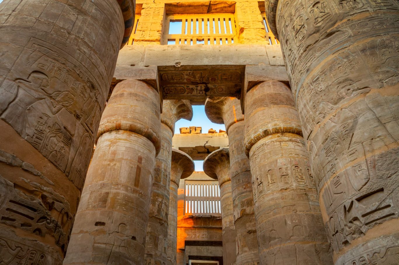 TOURS AND EXCURSIONS View of towering stone columns with intricate carvings and warm lighting.